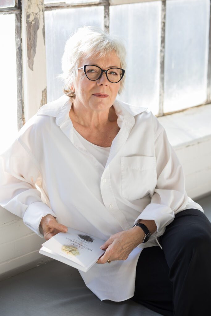 Diane Dubeau artiste visuelle et autrice assise avec son livre sur une résidence de création avec ses parents atteints de démence